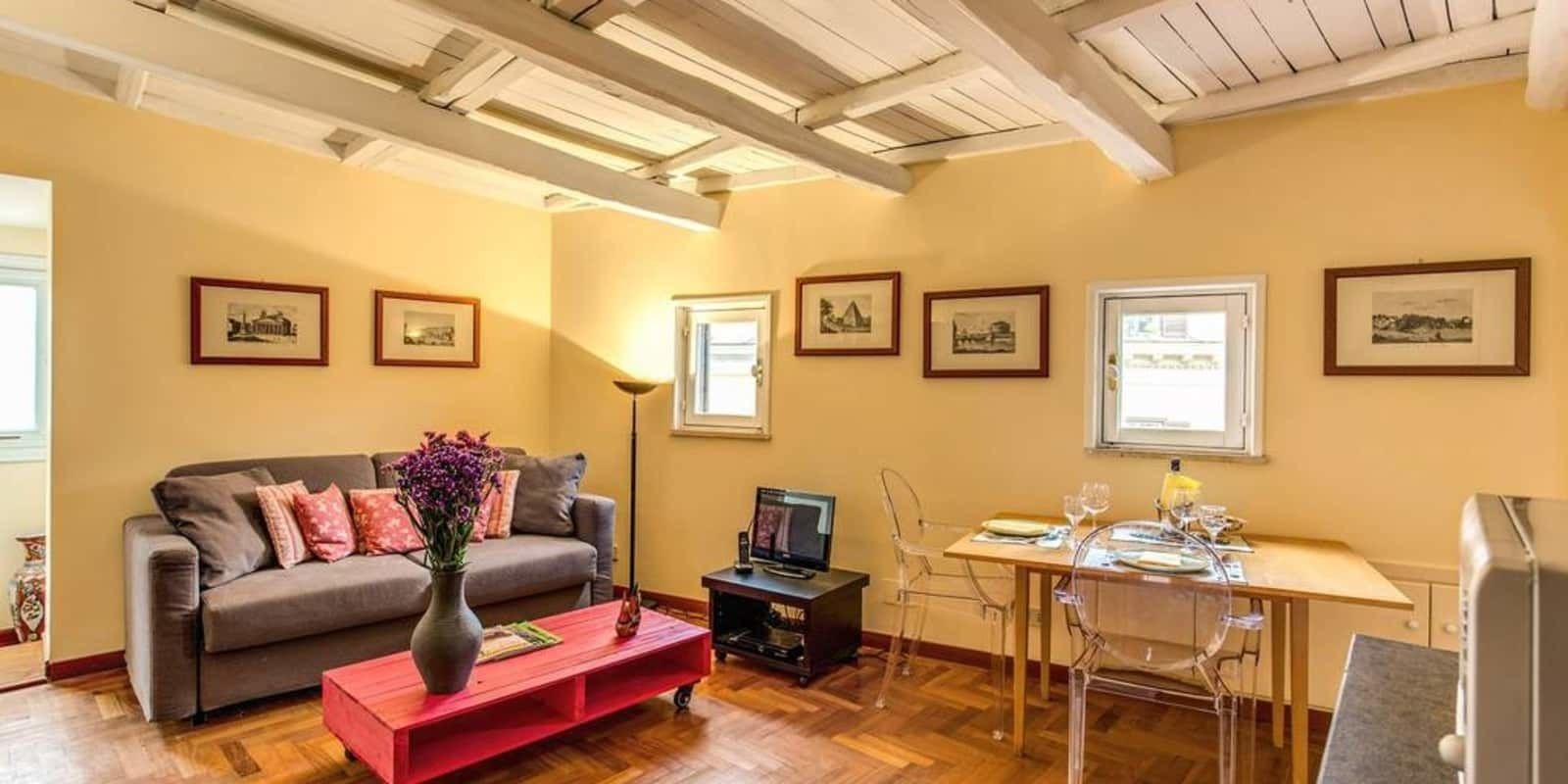 A living room with a sofa, coffee table, TV, and dining area with chairs and a table.