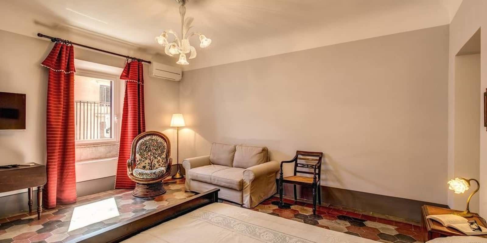Una habitación con sofá, una silla, una lámpara y un tapete estampado.