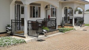 A modern house with a covered porch, a fire extinguisher, and a paved driveway. - Mamikki Hotel Apartment (Tororo)