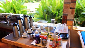 A breakfast setup with coffee makers, cups, and condiments on a table with a view of lush greenery. - Mamikki Hotel Apartment (Tororo)
