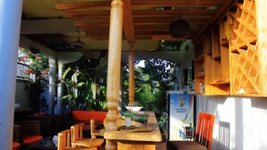 An outdoor seating area with wooden furniture and a wooden column. - Mamikki Hotel Apartment (Tororo)