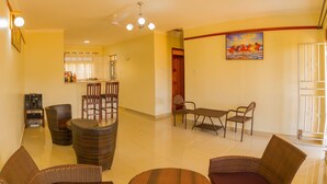 A spacious living area with wicker furniture, a dining table, and a kitchen in the background. - Mamikki Hotel Apartment (Tororo)