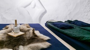 Una habitación con una cama, un manto de pieles y una botella de champán sobre una bandeja de madera.
