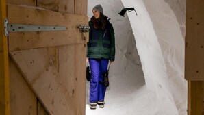 Una persona parada en un túnel cubierto de nieve con paredes de madera y una puerta.
