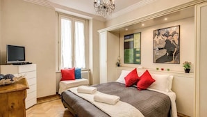 A bedroom with a bed, a dresser, a television, and artwork on the wall. - Roma Barocca Spanish Steps (Rome)