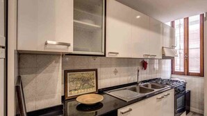 Une cuisine avec des meubles blancs, une cuisinière, un évier et une fenêtre.