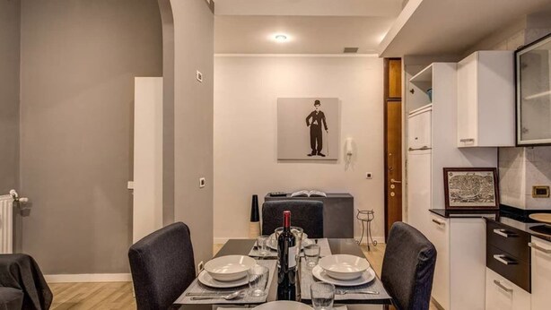 Un coin repas avec une table dressée pour deux personnes, un réfrigérateur et un four à micro-ondes dans la cuisine adjacente.