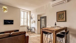 Una sala moderna con una mesa de comedor de madera, un sofá de cuero y un televisor montado en la pared.