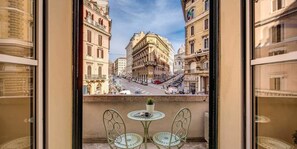 A balcony with two chairs and a small table, overlooking a street with historic buildings and a clear sky. - Cavour Colosseum with Balcony (Rome)