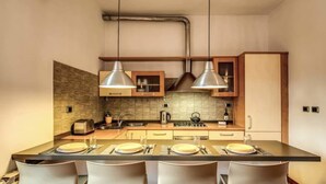 A modern kitchen with a central island, stainless steel appliances, and pendant lighting. - Attic terrace with St Peter's Dome View (Rome)