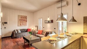 A modern kitchen with a central island, pendant lighting, and a dining area with a table set for four. - Attic terrace with St Peter's Dome View (Rome)