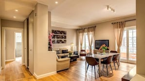 Un salon moderne avec un canapé, une table à manger et des chaises. Un téléviseur est fixé au mur et il y a une fenêtre avec des rideaux.