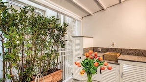 Une cuisine moderne avec des meubles blancs, un plan de travail en granit et une plante en pot.