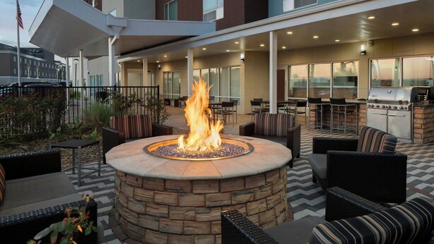 Un patio al aire libre con una chimenea de piedra, asientos y una zona de parrilla.