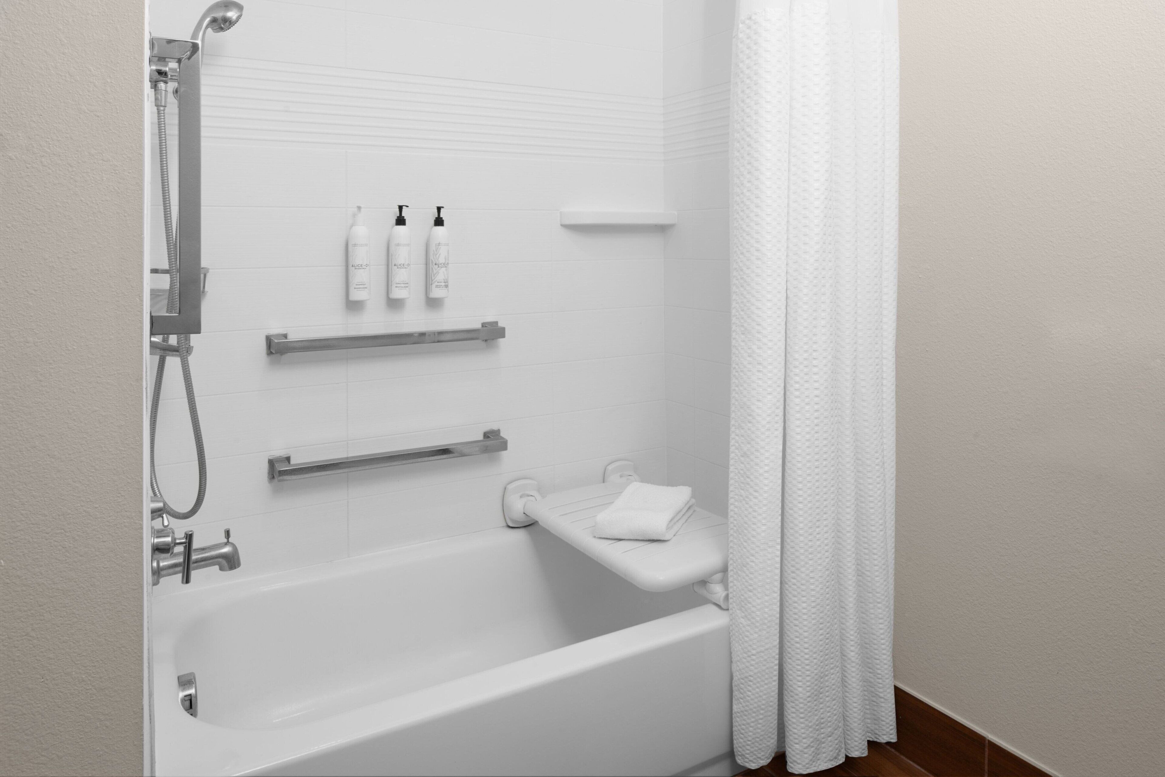 Une salle de bain moderne équipée d’une baignoire, d’une douche, d’un porte-serviettes et d’une étagère pour les articles de toilette.