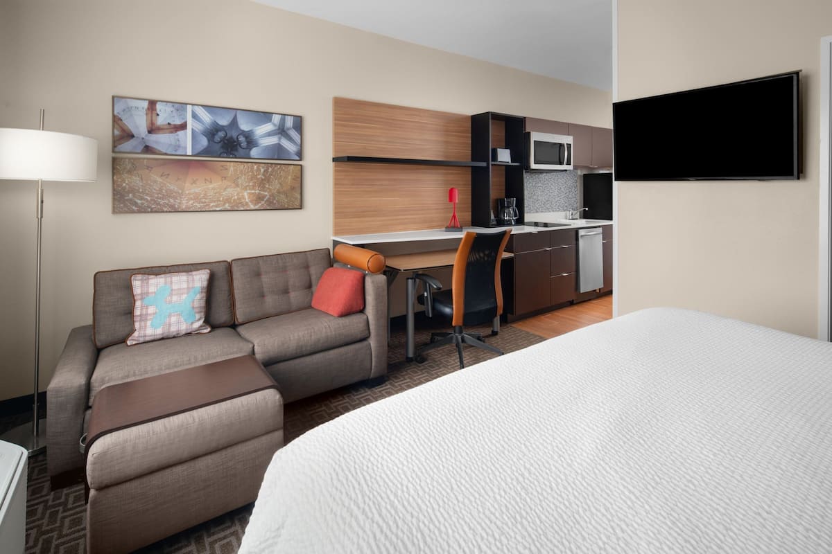 Habitación de hotel con cama, sofá, escritorio, silla, televisión de pantalla plana y kitchenette.