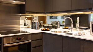 A modern kitchen with stainless steel appliances, a built-in oven, and a large island with a sink and kettle. - HomefromHolme Alban House (St Albans)