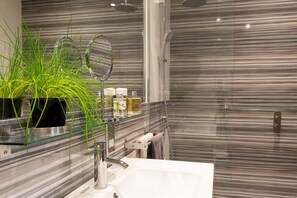 A modern bathroom with a glass shelf holding a plant, a mirror, and toiletries. - HomefromHolme Alban House (St Albans)