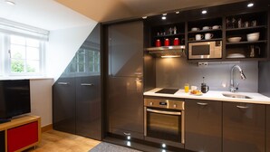 A modern kitchen with dark cabinets, a microwave, a sink, and a stove. - HomefromHolme Alban House (St Albans)
