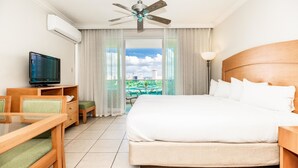 Habitación de hotel con cama, televisión, escritorio, silla y balcón con vistas a la ciudad.