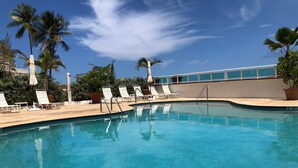 A clear blue pool with white lounge chairs and palm trees in the background. - Condado Lagoon Hospitality (San Juan)