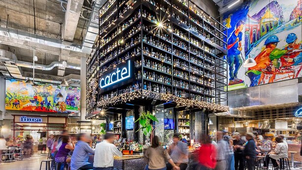 A bar area with multiple shelves of bottles, a neon sign, and a mural on the wall. - Condado Lagoon Hospitality At Paseo Caribe (San Juan)