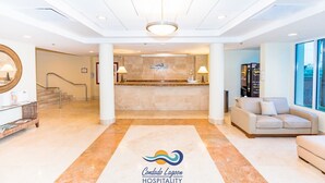 A hotel lobby with a reception desk, a staircase, a sofa, and a coffee machine. - Condado Lagoon Hospitality At Paseo Caribe (San Juan)