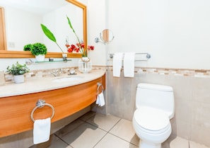 A modern bathroom with a wooden vanity, a white toilet, and a mirror above the sink. - 524 Ocean Studio (San Juan)