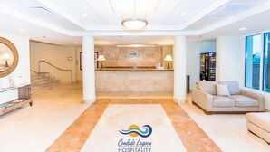 A hotel lobby with a reception desk, a staircase, a sofa, and a large window. - 524 Ocean Studio (San Juan)