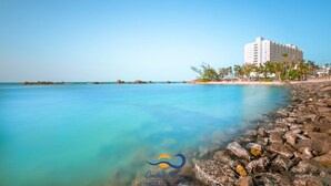 A coastal hotel with a clear view of the ocean, a rocky shoreline, and a building with multiple floors and balconies. - 510 Ocean Studio (San Juan)