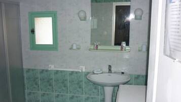 Een badkamer met een spiegel met groene lijst, een wastafel en een toilet.