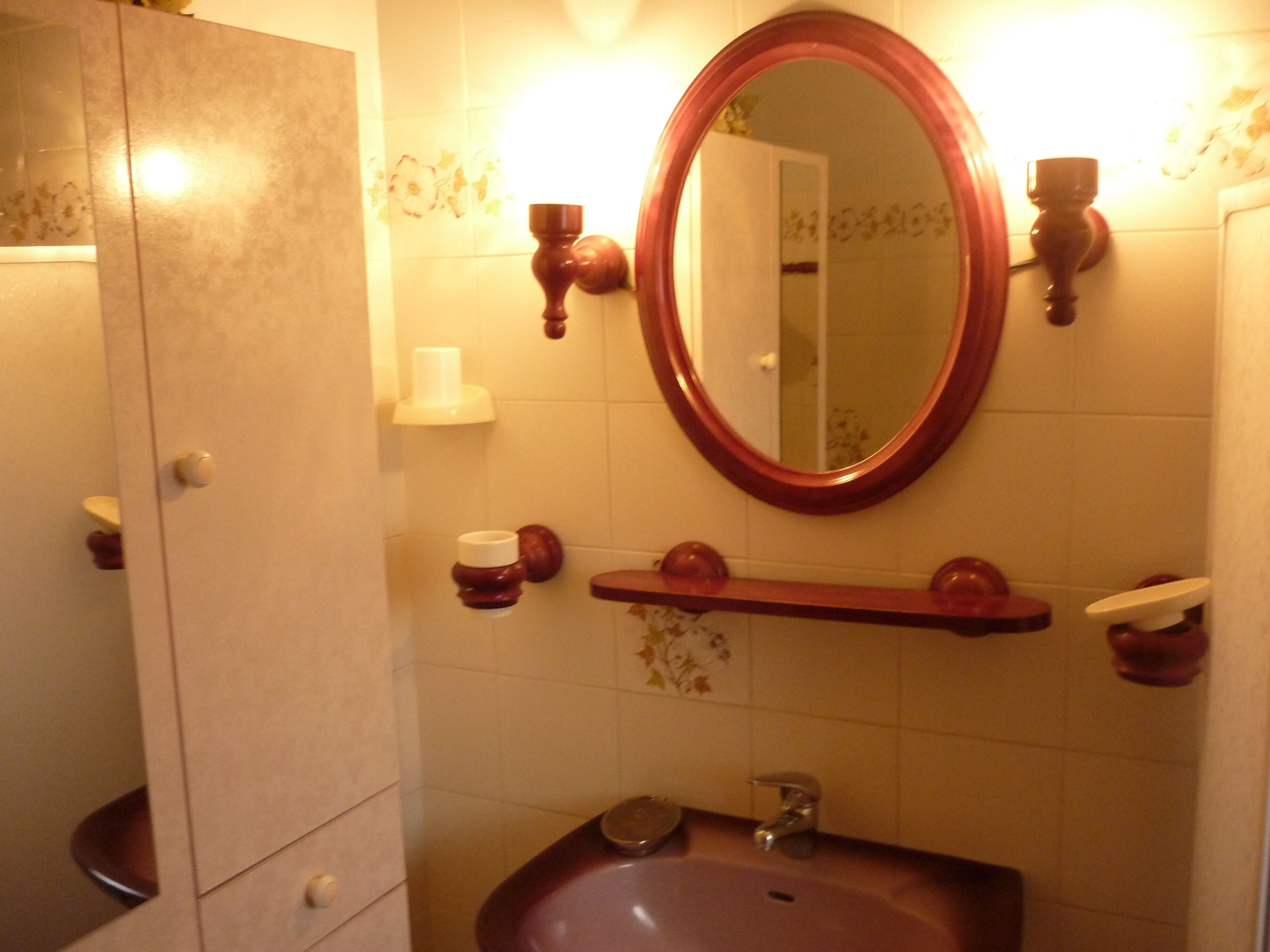 A bathroom with a marble sink, a mirror, and a wooden shelf.