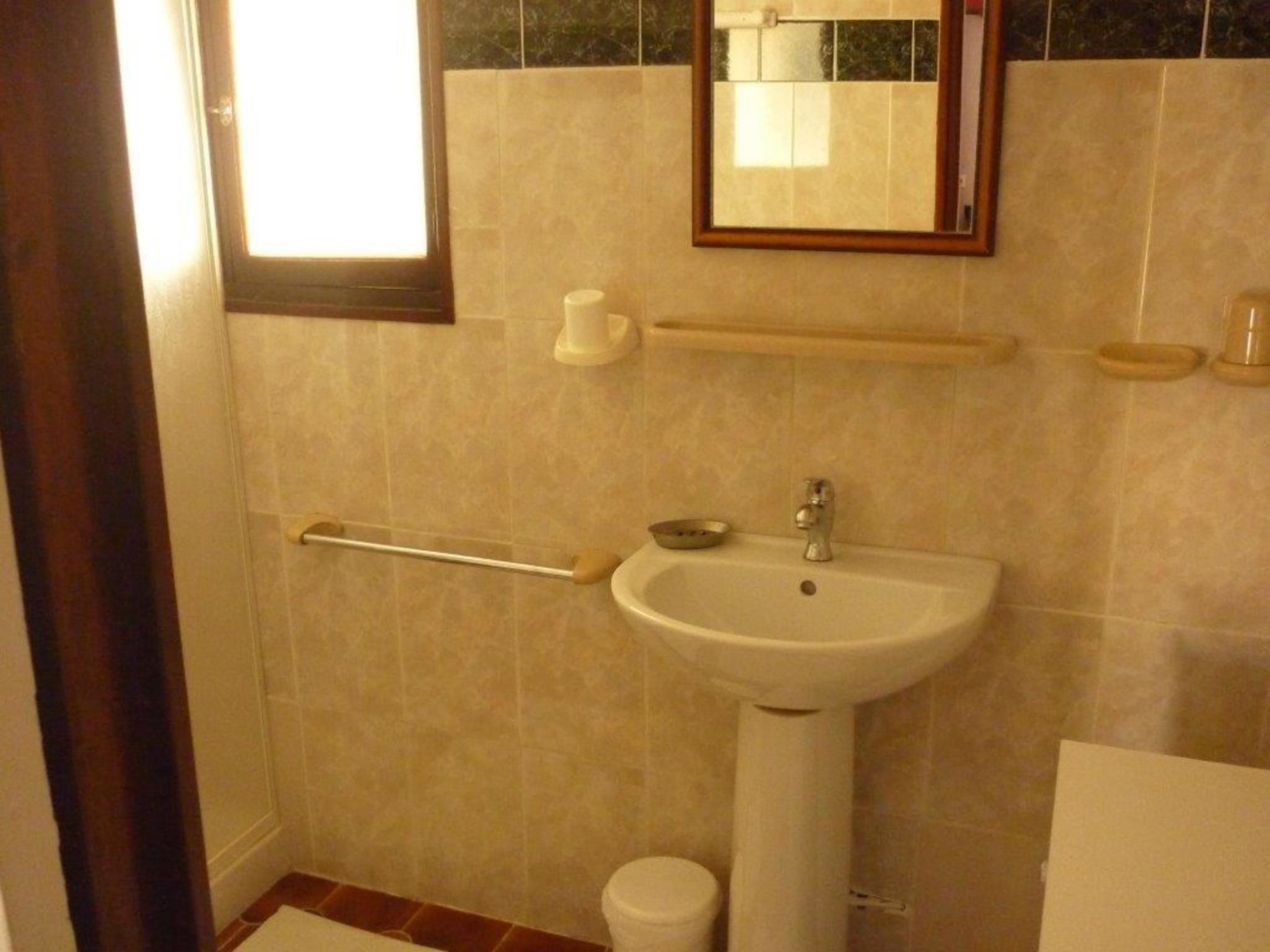 Et badeværelse med håndvask, spejl og toilet.
