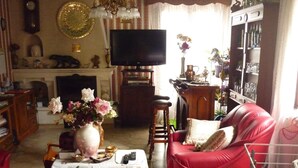 A living room with a red leather sofa, a television, a fireplace, and a bookshelf. - Domaine de la Rode Buze (Cahors)
