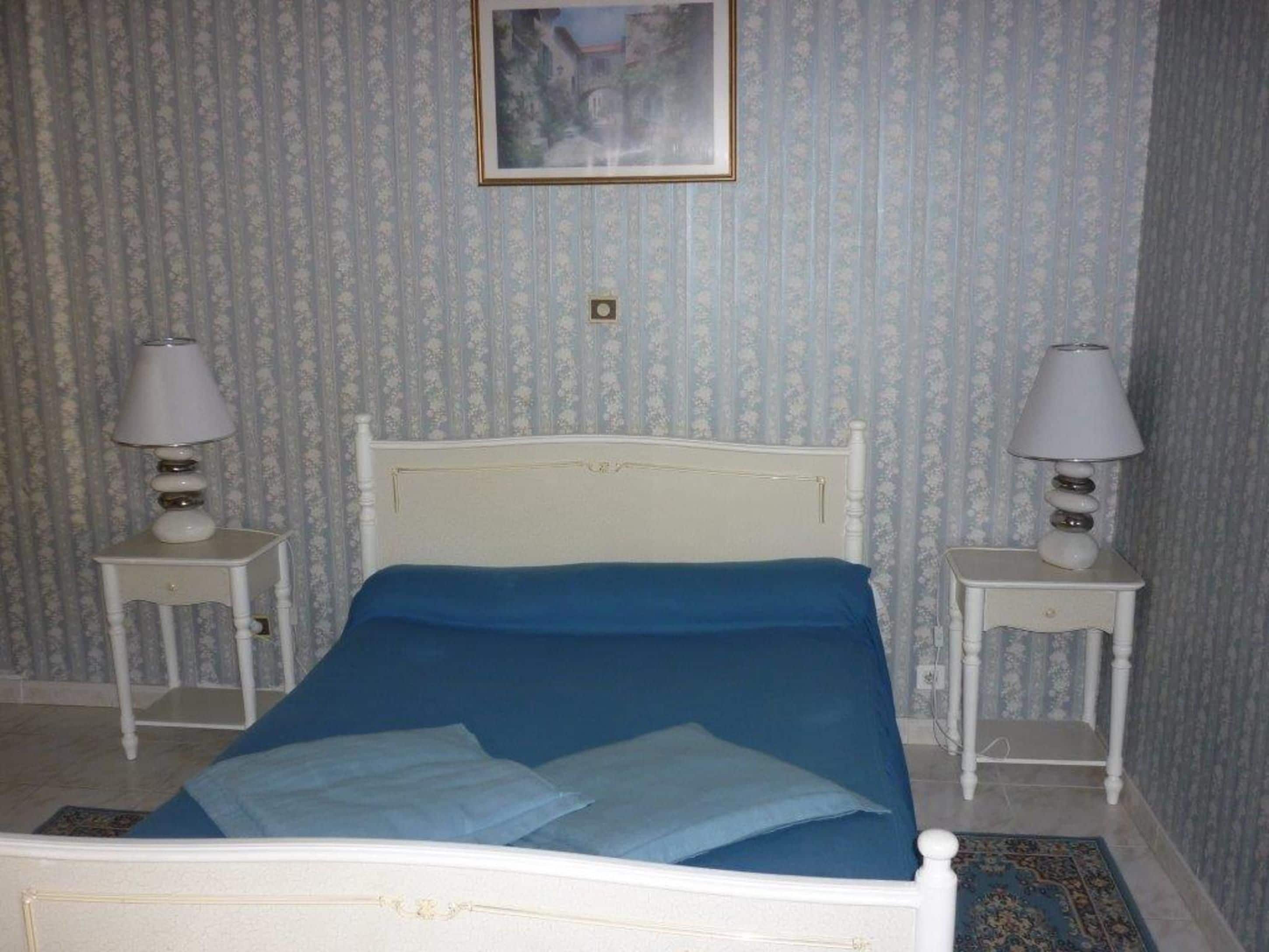 Un dormitorio con cama, dos mesitas de noche y un cuadro en la pared.