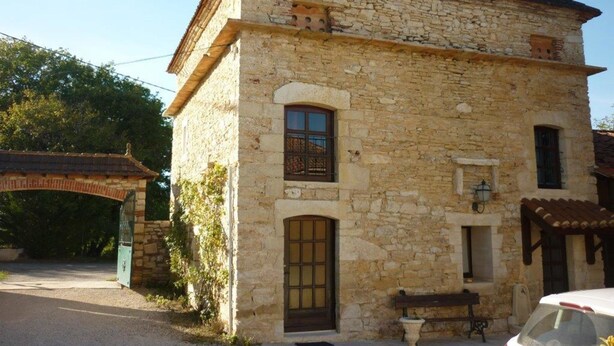 A stone building with a pitched roof, a small balcony, and a gate. - Domaine de la Rode Buze (Cahors)