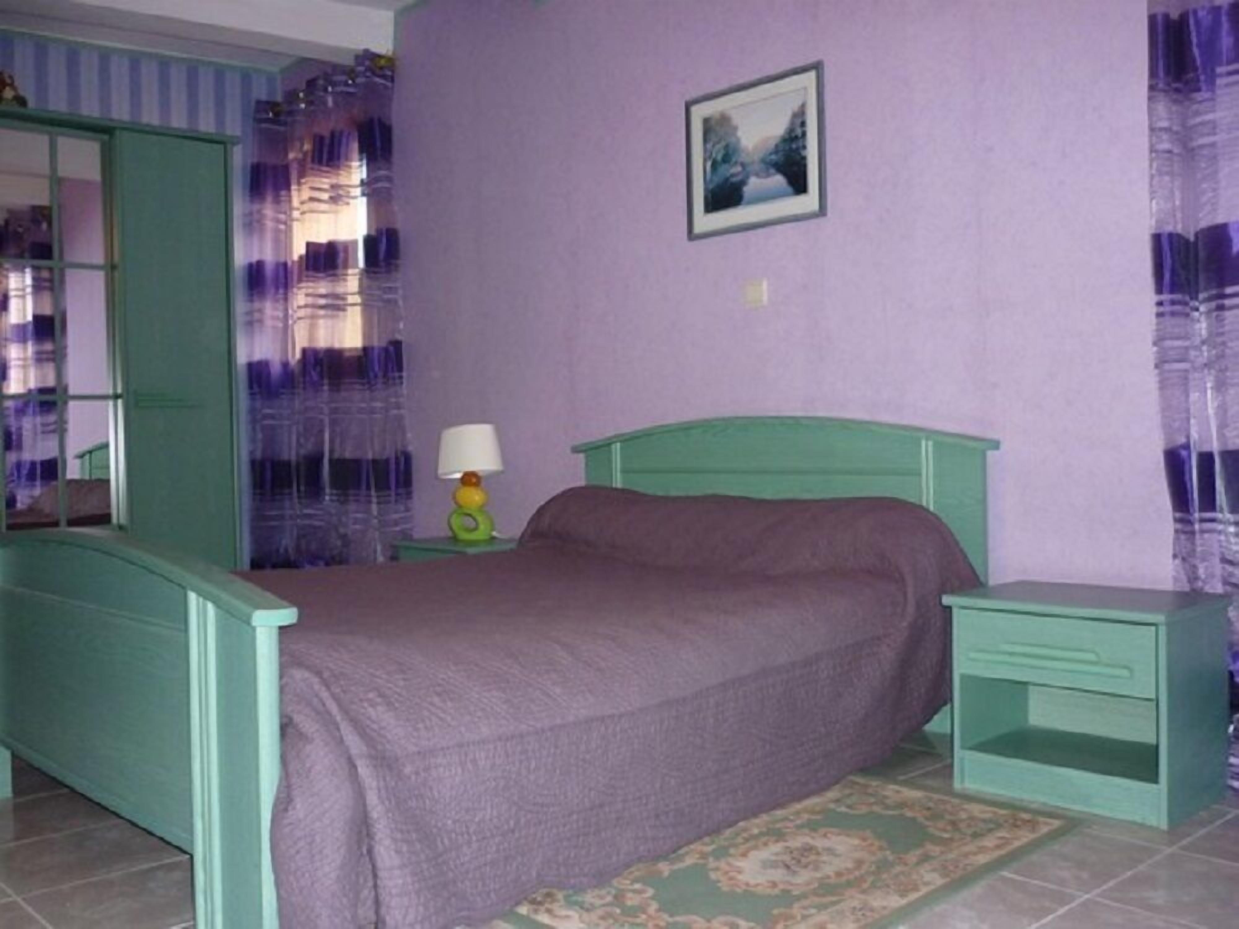 Ein Schlafzimmer mit Bett, Nachttisch, Lampe und einem Bild an der Wand.