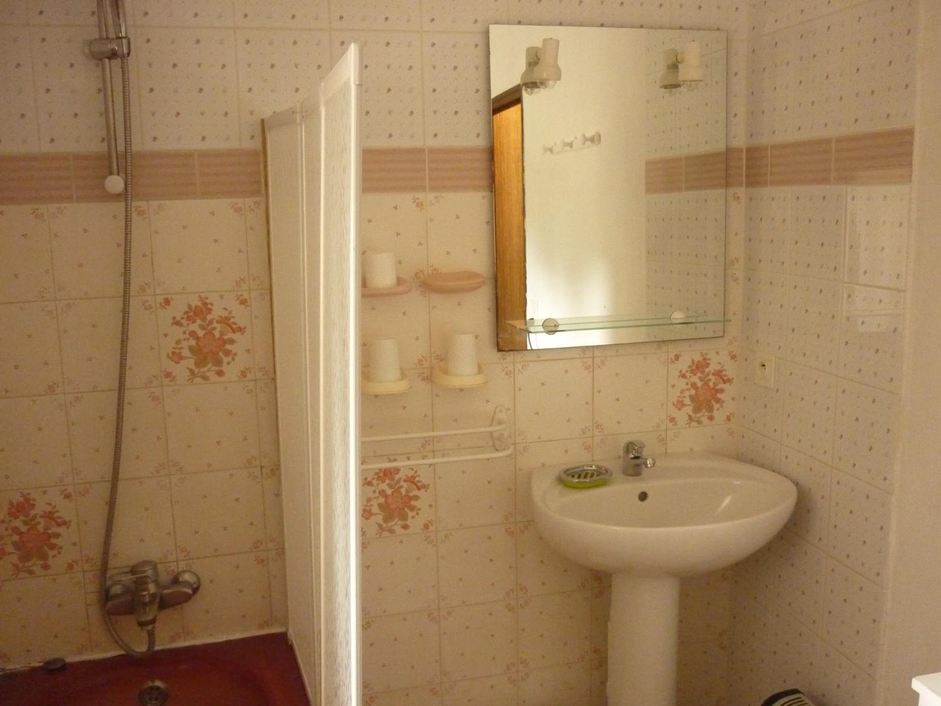 Un baño con ducha, lavabo y espejo.