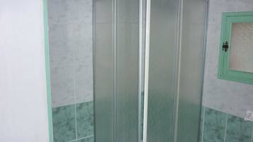 A glass-enclosed shower stall with a green frame, tiled walls, and a white door.