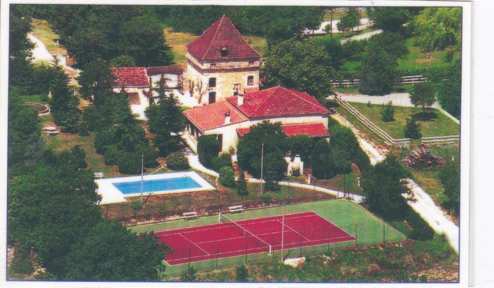 Vista aérea de una propiedad con un edificio central, una piscina y canchas de tenis.