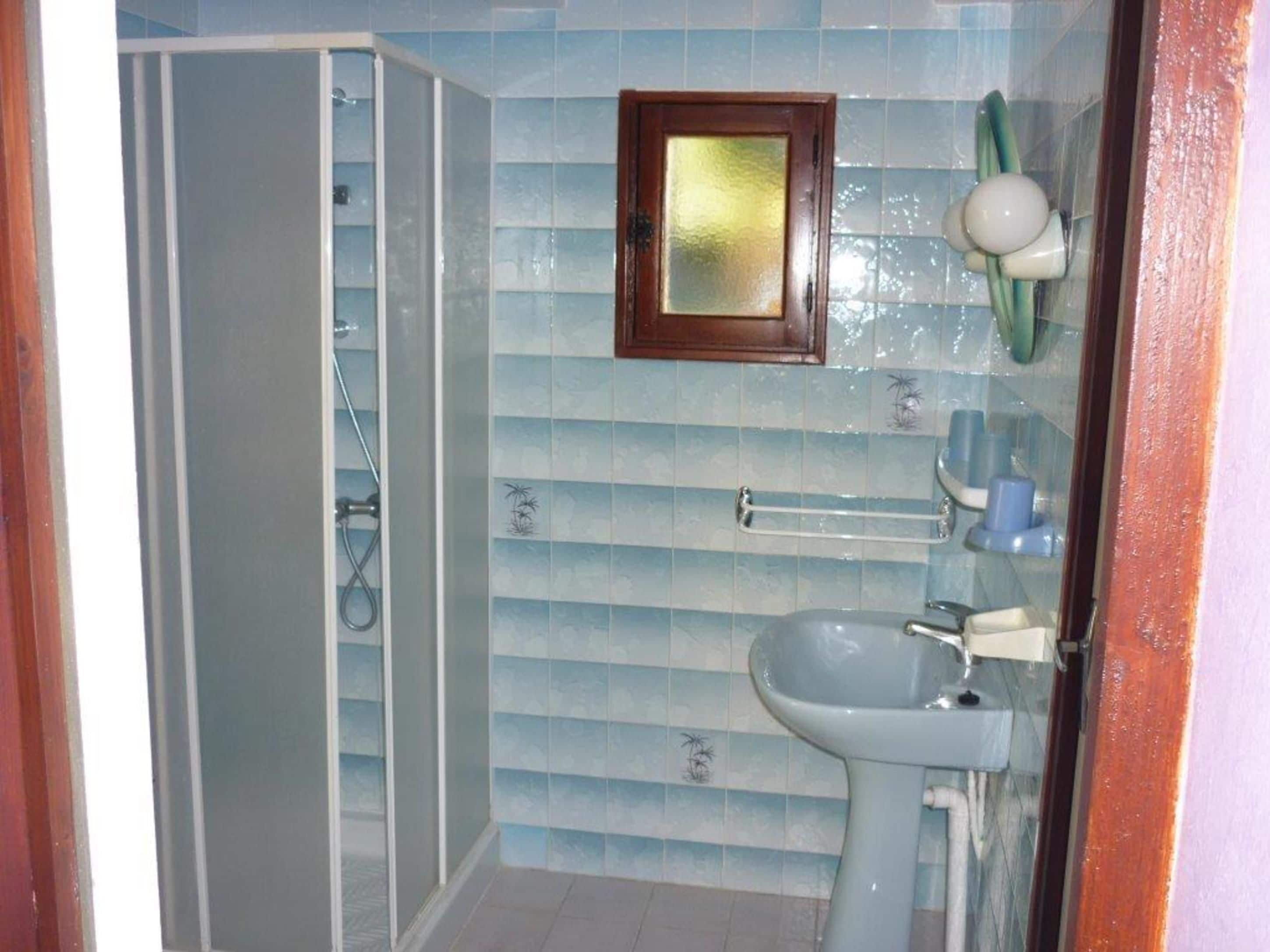 Een badkamer met een douche, een wastafel en een handdoekrek.