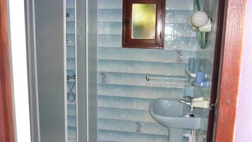 A bathroom with a shower, a sink, and a towel rack.
