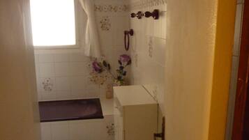A small bathroom with a window, a sink, a mirror, and a toilet.