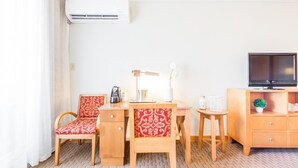 A hotel room with a bed, a desk with a chair, a TV, and an air conditioner. - 825 SEA & SUN Suite (San Juan)