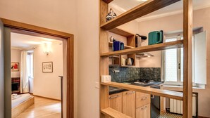 Una cucina moderna con mensole in legno, zoccolo piastrellato e un piccolo angolo pranzo con una panca.