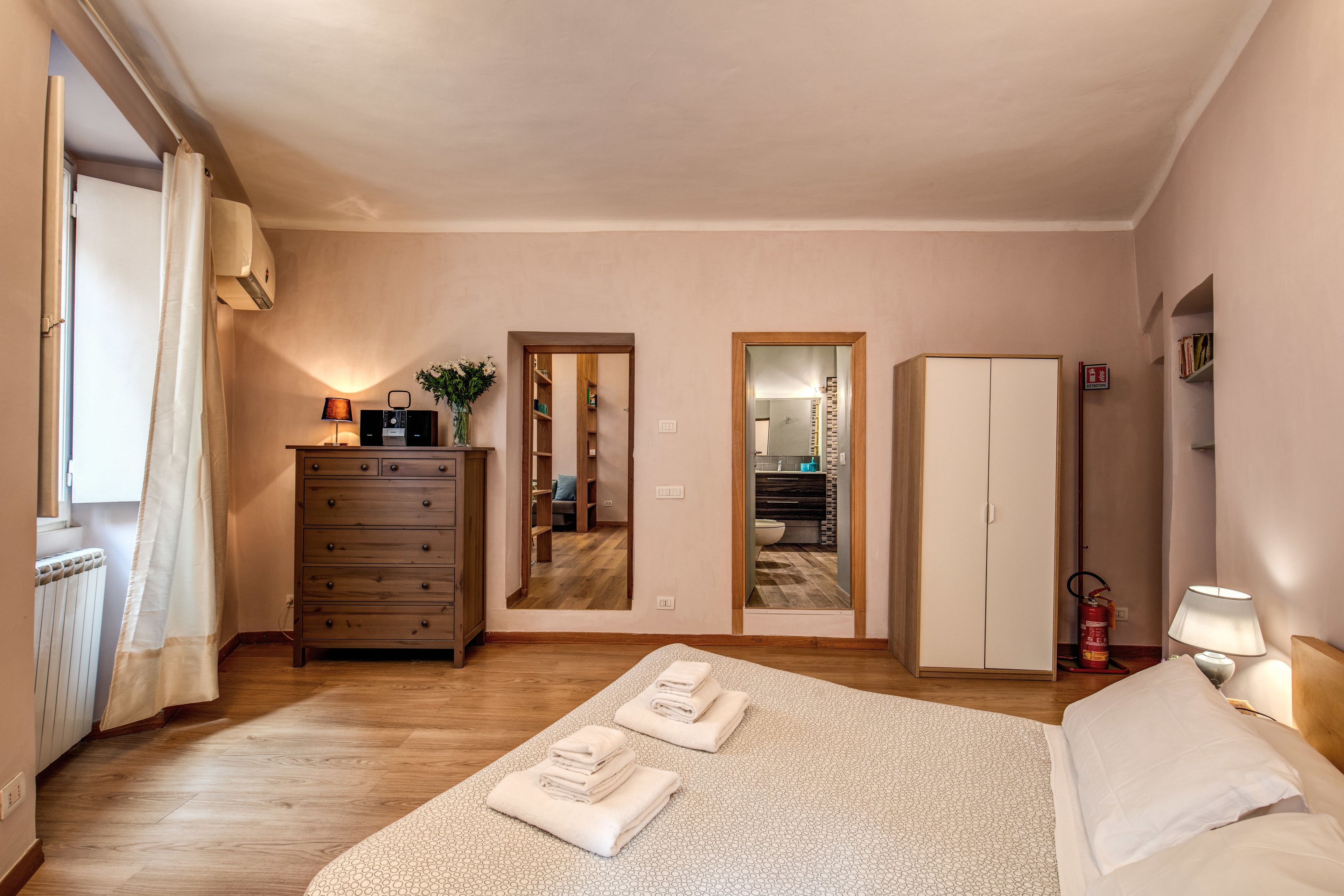Une chambre à coucher comprenant un lit, une commode, une armoire et une salle de bain visible à travers une porte.