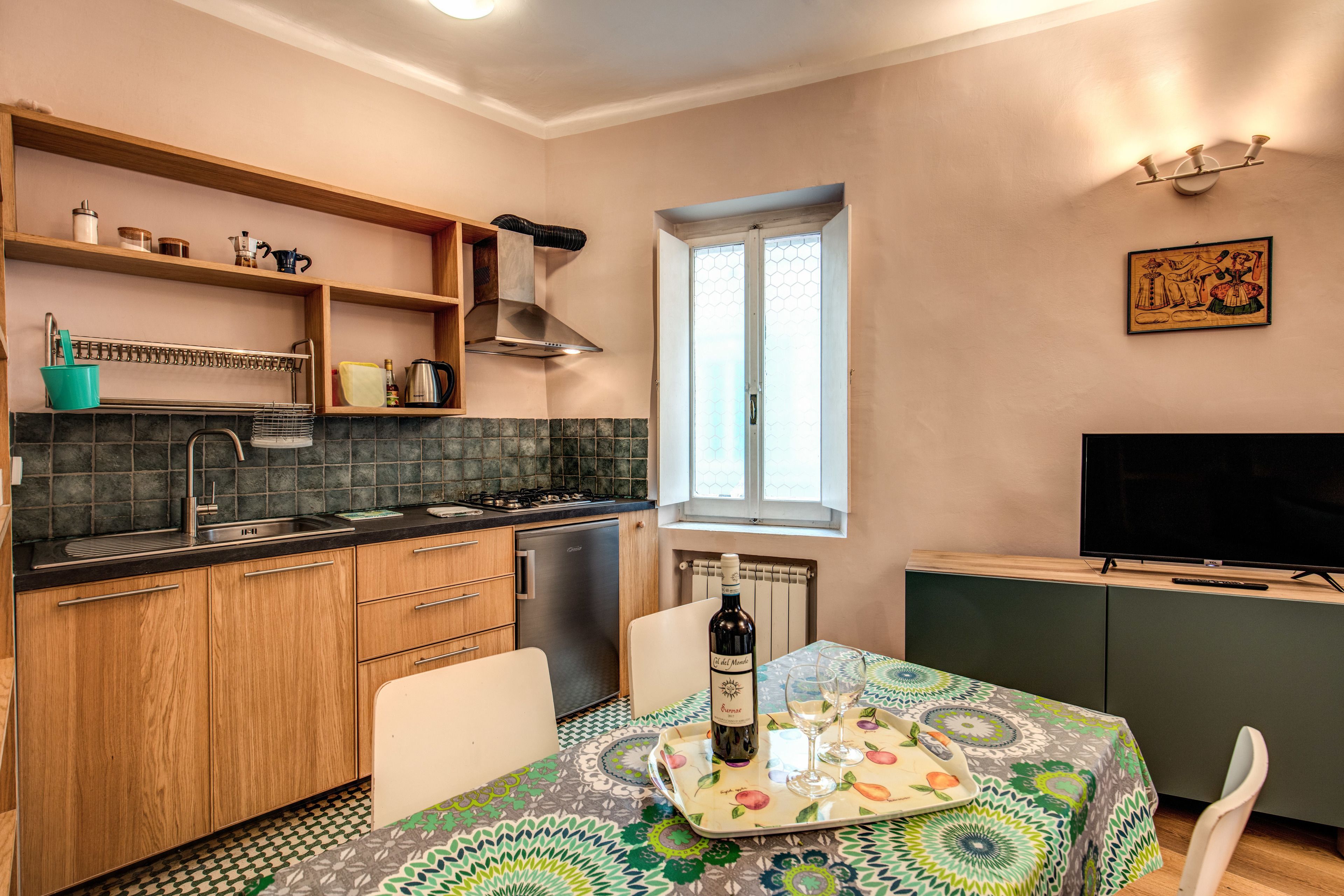 Une cuisine compacte avec des meubles en bois, une cuisinière encastrée et un coin repas avec une table dressée pour deux personnes.