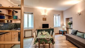 Un soggiorno moderno con zona pranzo, mobili contenitori in legno, televisore e divano.