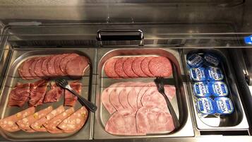 Mostrador de delicatessen con diferentes carnes y yogur Danone.