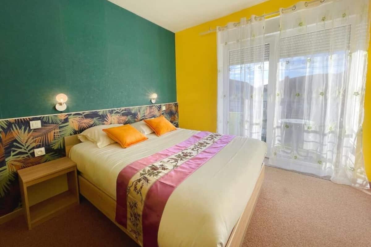 Un dormitorio con cama, mesita de noche y ventana con cortinas.